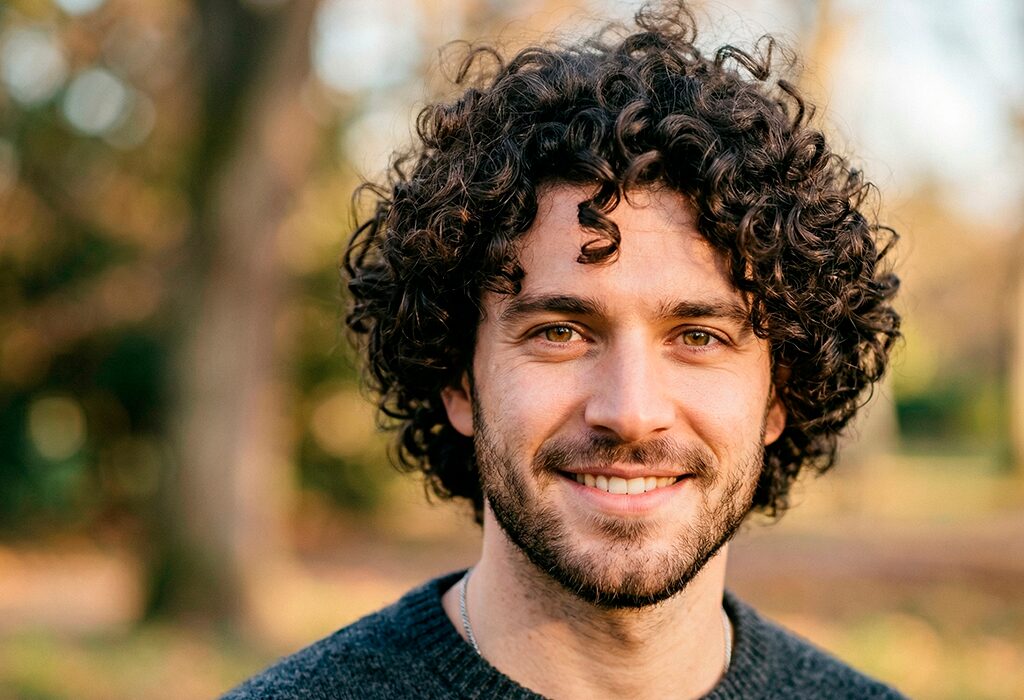Man with curly hair outdoors in soft light showing defined curls and natural texture