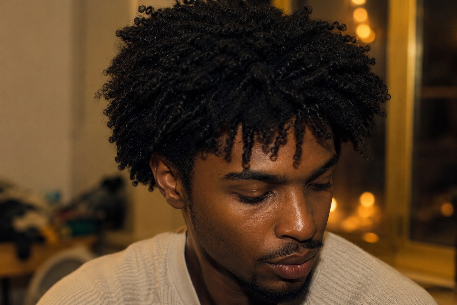 Close-up of a man with short kinky curls and naturally textured men’s hair.
