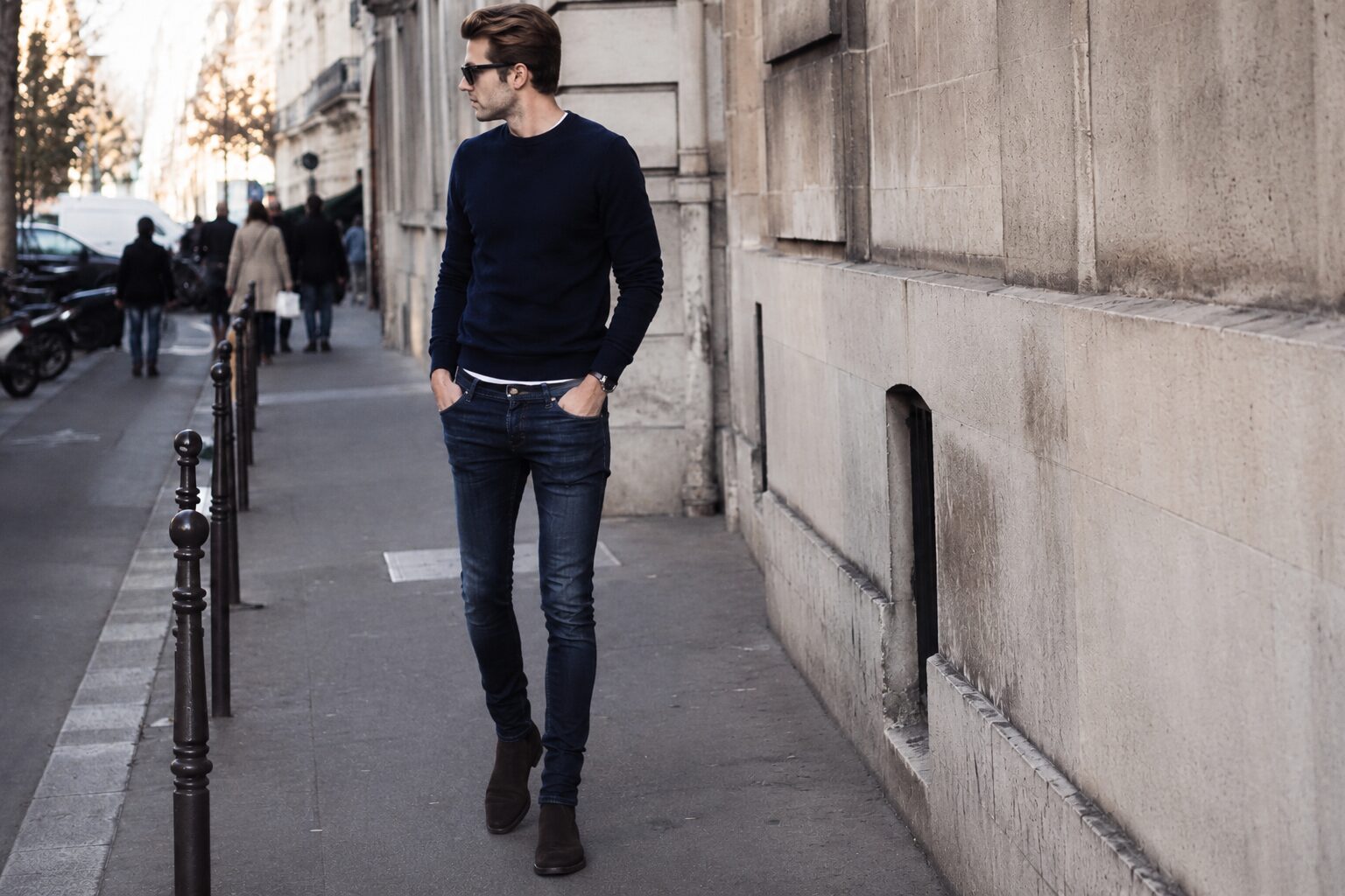 Stylish man in dark skinny jeans walking through city street with slim compressed silhouette.