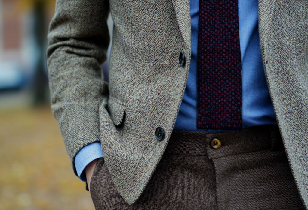 brown tweed sport coat with a blue oxford shirt and dark red knit tie with a squared end
