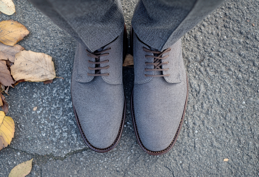 grey suede Oxford shoes with brown laces, worn with grey flannel trousers