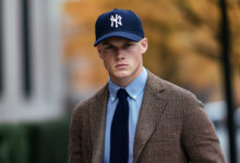 man wearing a brown tweed sport coat with navy blue Yankee logo baseball cap