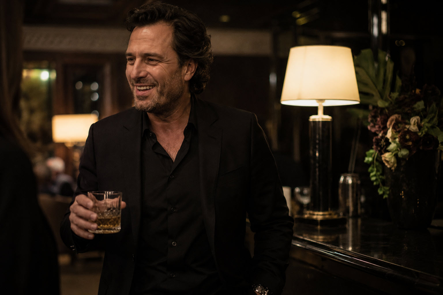 man in an all-black suit and black shirt at an evening event