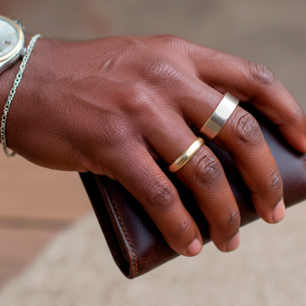 Black man’s hand with gold and silver rings, mixed-metal watch, holding wallet