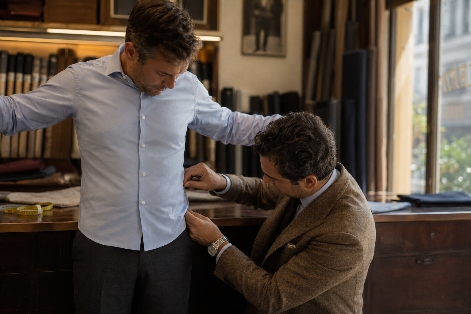 man in his mid-30s with a compact, short-torso build standing in a small tailor's shop