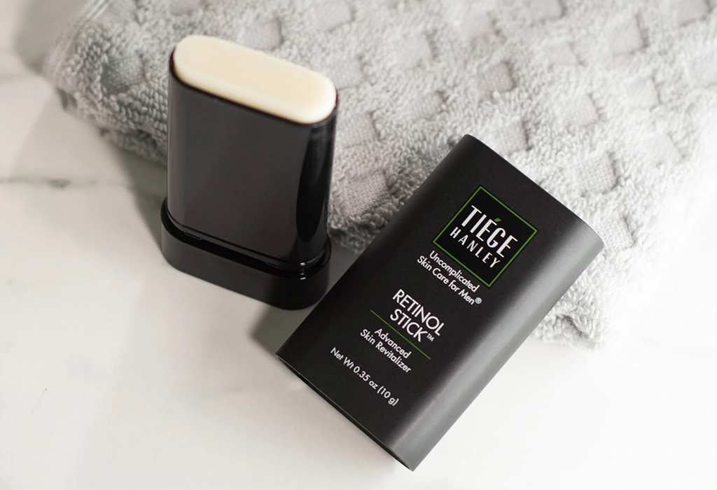 Tiege Hanley retinol stick and cap on countertop beside folded towel, clean setup