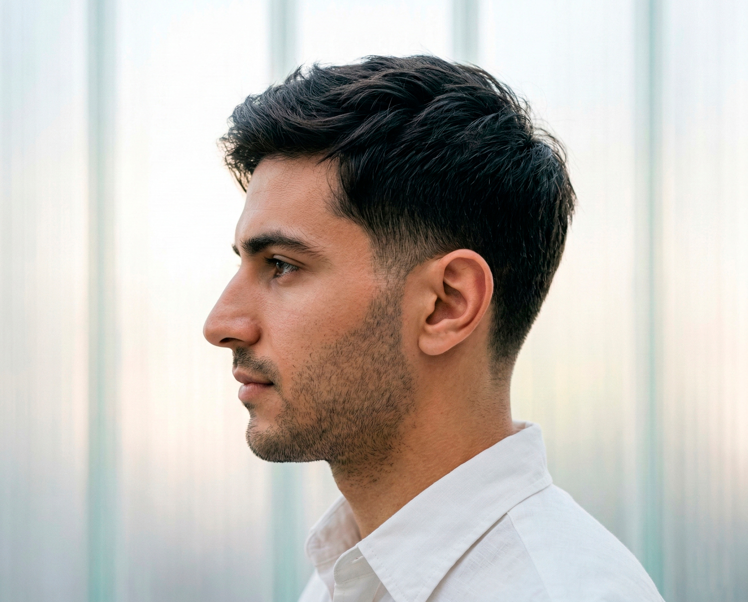 Man with textured Ivy League haircut featuring natural volume on top and tapered sides.