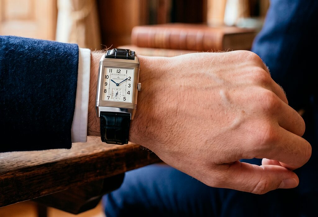 Rectangular dress watch worn with navy suit, shown close-up on wrist indoors.