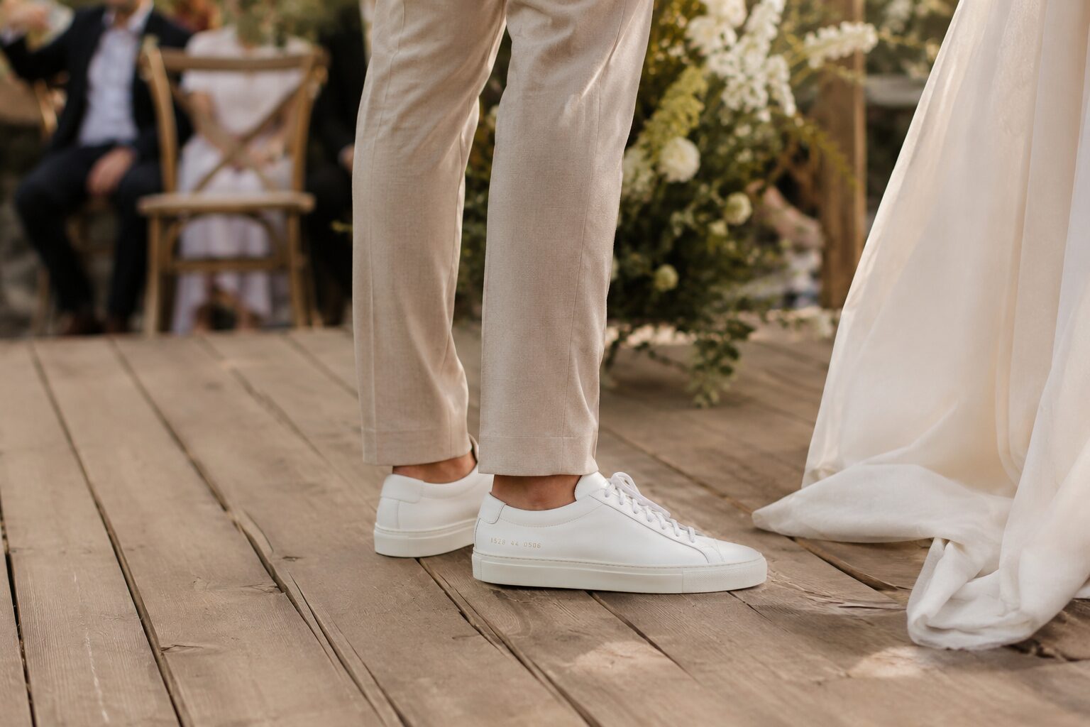White minimalist sneakers worn by groom with beige suit at casual wedding
